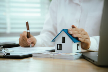 Real estate agents present home designs and discuss documents that reflect real estate investing,...