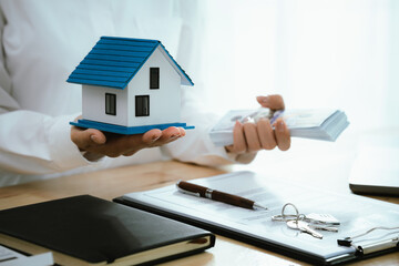 Real estate agents present home designs and discuss documents that reflect real estate investing,...