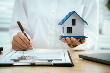 Real estate agents present home designs and discuss documents that reflect real estate investing,...
