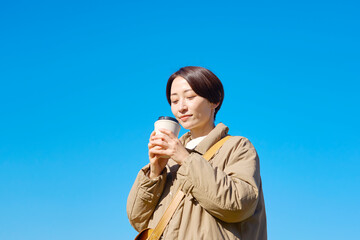 コヒーを飲むミドルエイジの女性　青空