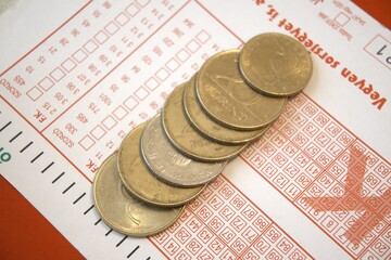 Close-up view of a Hungarian lottery ticket with scattered forint coins. Concept of luck, gambling,...