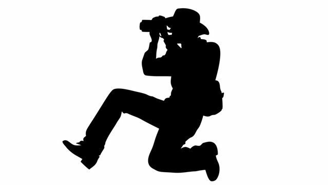 Silhouette of photographer in hat taking a picture in a dynamic pose with camera and bag slung on shoulder