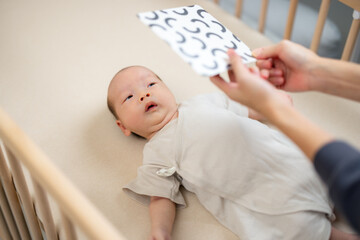 Newborn baby look at the contrast card on baby crib