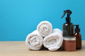 White towel and toiletries on wooden table with blue background
