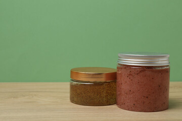Pink bottles of toiletries on a wooden table with a green background

