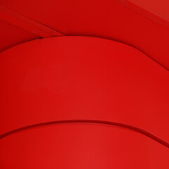 Three overlapping, smooth, red, curved surfaces creating a modern, abstract pattern with subtle shadows, emphasizing the vibrant red color and sleek, contemporary design.