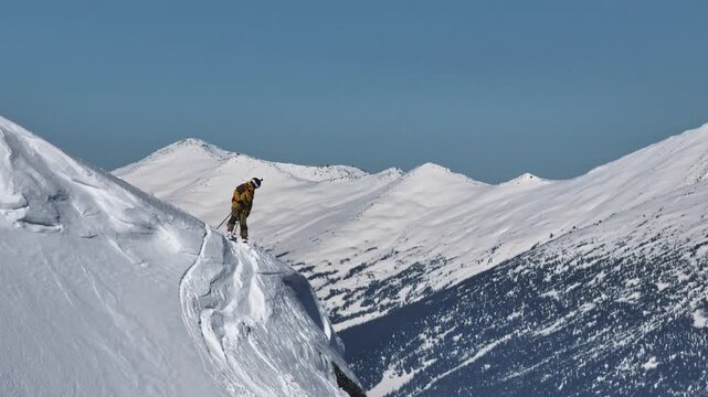 Skier evaluating snowy ridge line in mountain landscape