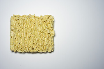 A close-up shot of a block of uncooked instant noodles, showing its distinctive wavy texture and shape, ready to be prepared.