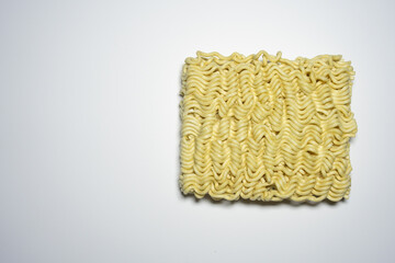 A close-up shot of a block of uncooked instant noodles, showing its distinctive wavy texture and shape, ready to be prepared.