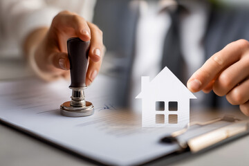 Signing and stamping housing ownership papers, legal real estate paperwork with house symbol