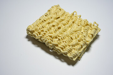 A close-up shot of a block of uncooked instant noodles, showing its distinctive wavy texture and shape, ready to be prepared.