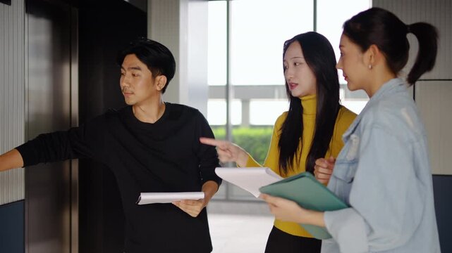 Group of young asian businesspeople passionately discusses key strategies while waiting for the elevator in a modern office, meeting with colleagues, communicate and use their free time descending