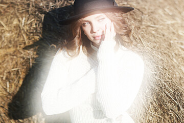 female look in a hat, a model posing in a field of straw