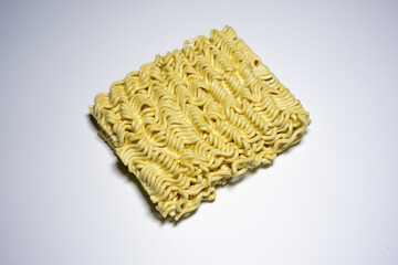 A close-up shot of a block of uncooked instant noodles, showing its distinctive wavy texture and...
