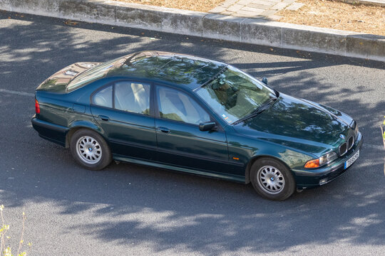 Green bmw 5 series e39 sedan driving on asphalt road