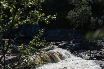 streams of clear waterfall water and stone banks of a mountain river