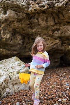 Family holiday at seaside. Little girl picking stones at the beach