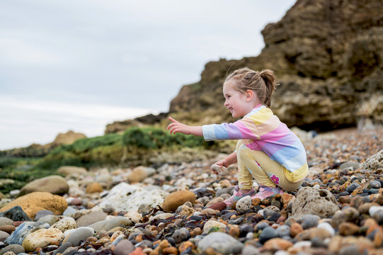 Family holiday at seaside. Little girl picking stones at the beach