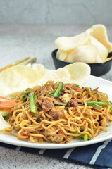 Indonesian fried noodles with egg, chicken, mustard greens, and crackers