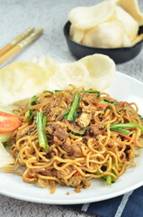 Indonesian fried noodles with egg, chicken, mustard greens, and crackers