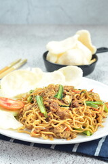 Indonesian fried noodles with egg, chicken, mustard greens, and crackers