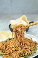 Indonesian fried noodles with egg, chicken, mustard greens, and crackers
