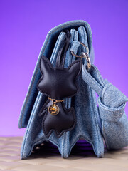 Close-up of a black  leather bag charm in the shape of a cute fox  on blue bag