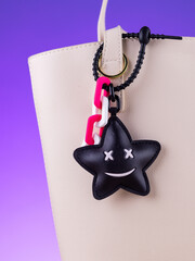 Close-up of a black leather bag charm in the shape of a funny star   on white bag