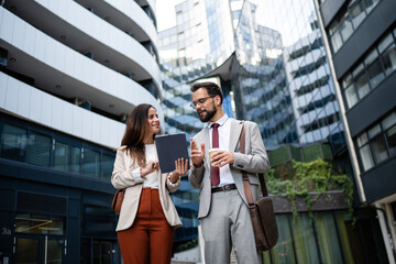 Businesspeople walking and talking using tablet in urban city center