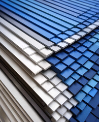  A structured array of rectangular tiles in various shades of blue, white, and gray, arranged to create a textured and slightly overlapping pattern with a modern, almost architectural feel.