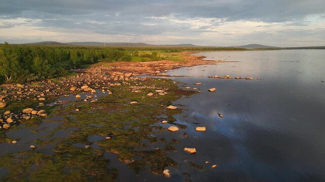 Drone shot of the shoreline of Stora Lulevatten, with forest and hills in Norrbotten County, Sweden