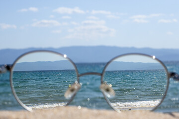 Clear sea view through glasses on a sunny beach.