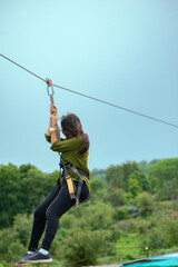 Young woman ziplining, harness secured, India adventure, dynamic composition.