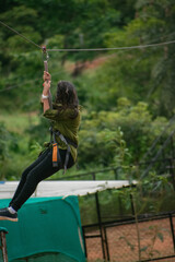 Young woman zip-lining through lush green canopy in India.  Acti