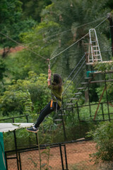 Young woman zip-lining through lush Indian jungle. Action shot, adventurous activity.