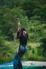 Young woman ziplining, enjoying adventurous activity amidst lush green Indian landscape.