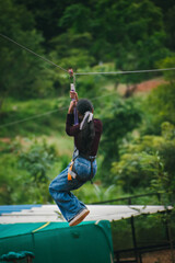Young woman ziplining, enjoying adventurous activity amidst lush green Indian landscape.