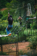Young woman zip-lining through lush Indian forest, adventurous a