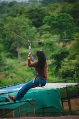 Young woman ziplining through lush green landscape in India. Dynamic action shot.
