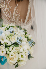 The bride is wearing a white dress embroidered with various ornaments, with a gold wedding ring on...