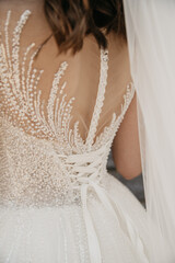 The bride in a white dress embroidered with various ornaments shows the deep neckline on the back...