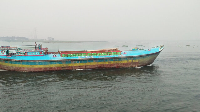 Side view of a large sand bulkhead transporting materials, an industrial landscape of a river in Bangladesh.