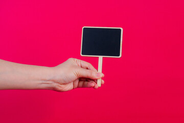 Empty post blackboard in hand isolated on red background.