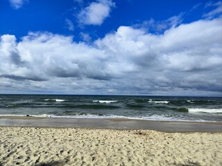 Sandy beach with waves and dramatic cloudy sky