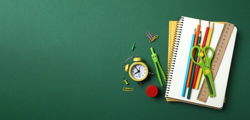 Collection of school supplies including notebook, pencils and stationery on colored background