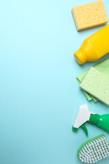 Vertical photo with cleaning products including bottle, sponge, spray on blue background. Flat lay...