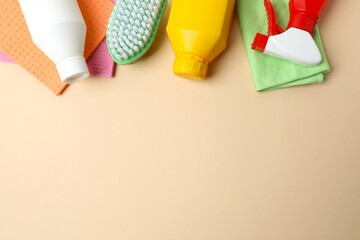 Household cleaning supplies including brush, sponges, and bottles arranged as a frame on a color...
