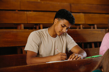 Focused Student Taking Notes in a Wooden Lecture Hall Environment