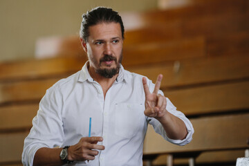Male Educator Discussing Ideas in a Classroom Setting with Expressive Hand Gestures