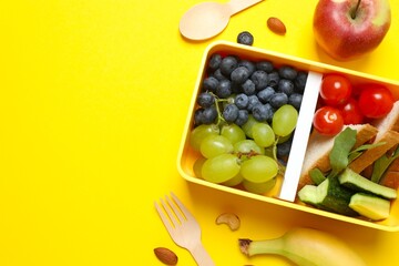 Packed lunch with sandwiches, fruits, nuts and vegetables in a divided container
